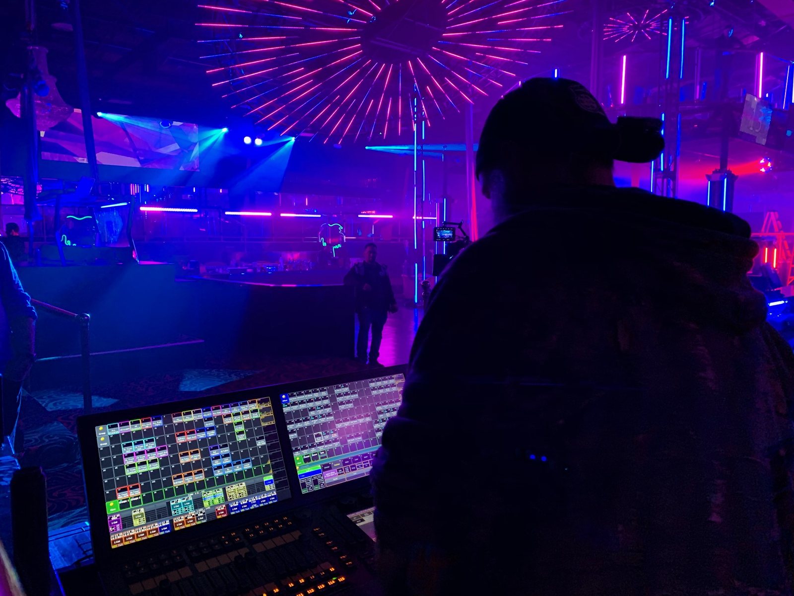 Matt programming lighting at the console during a live event, with LED and beam effects across the venue